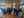 Un cercle de personnes assises dans une salle de bois lumineuse participe à une rencontre animée par une femme.